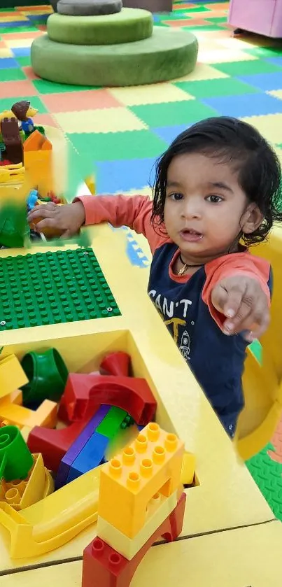 Child playing in colorful toy area with building blocks.