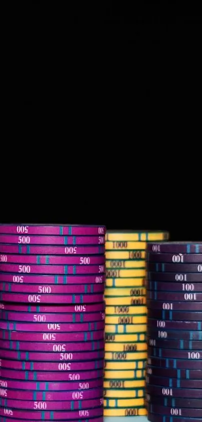 Hand stacking colorful poker chips on a light blue table against a black background.