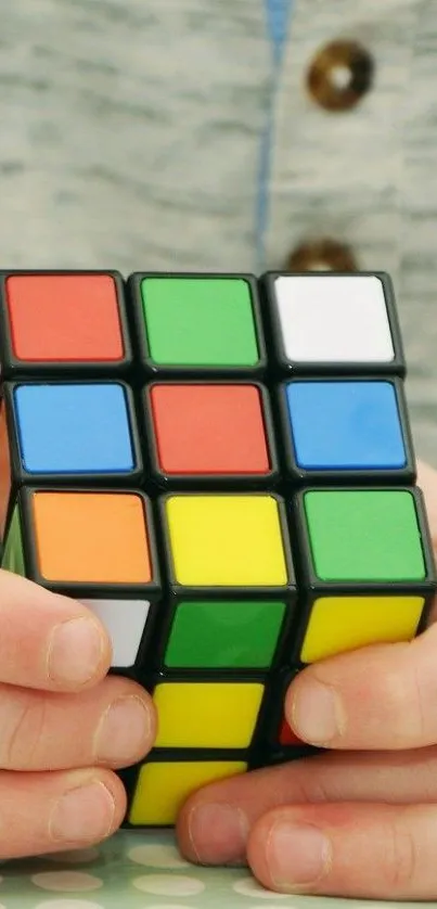 Mobile wallpaper of a colorful puzzle cube held in hands.