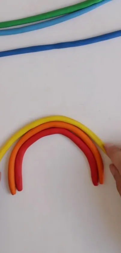 Handmade clay rainbow on white background with bright colors.