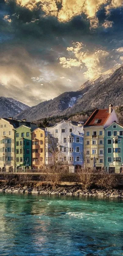 Colorful European townscape by a river with mountains in the background.