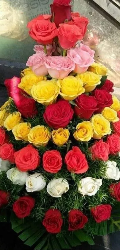 Pyramid of colorful roses arrangement with green leaves.