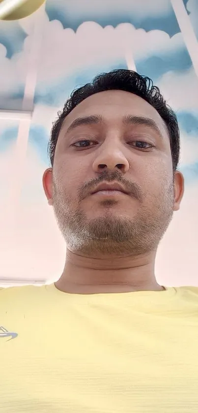 A selfie of a man wearing a yellow shirt under a cloudy sky.