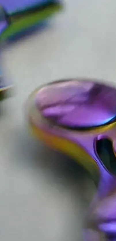 Close-up of a shiny, rainbow-colored fidget spinner on a mobile wallpaper.