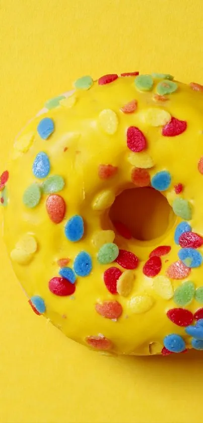 Yellow donut with colorful sprinkles on a yellow background.