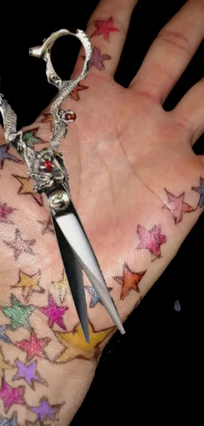 Hand with colorful star tattoos and ornate scissors on black background.