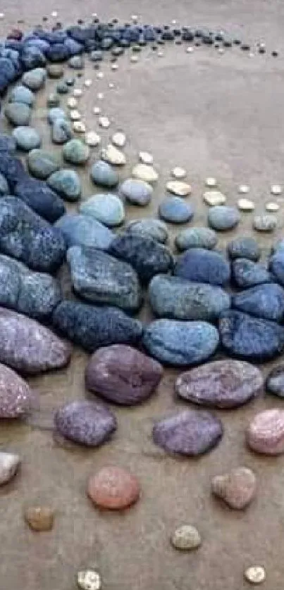 Spiral arrangement of colorful stones on sand.