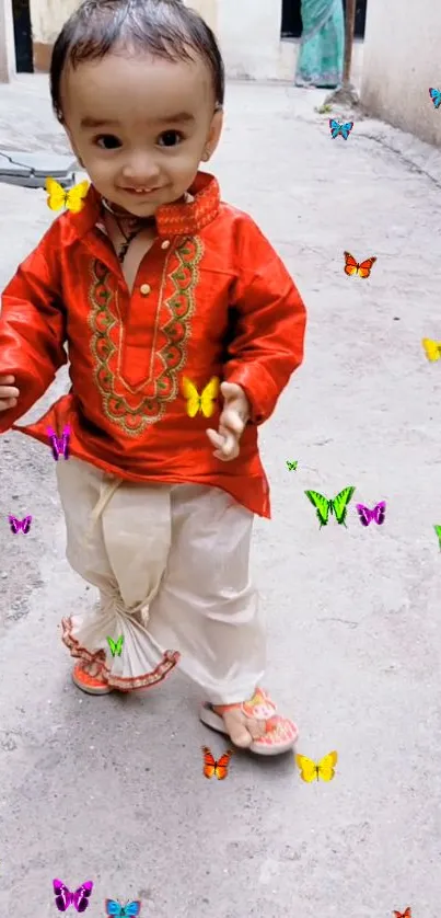 Toddler in red outfit with colorful butterflies.