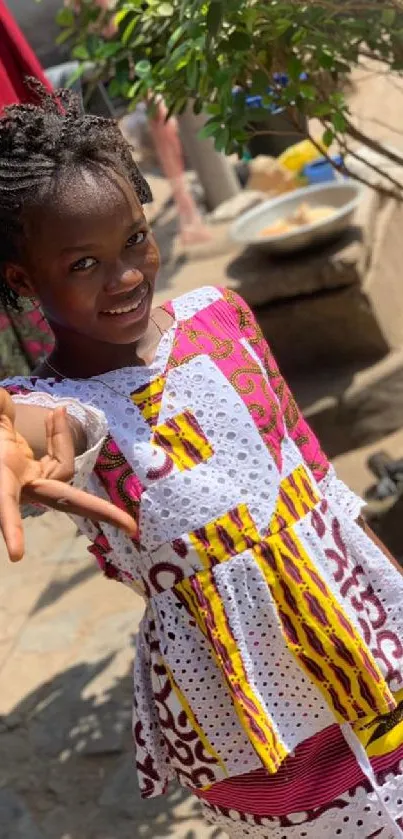 Young girl in colorful traditional attire smiling outdoors.