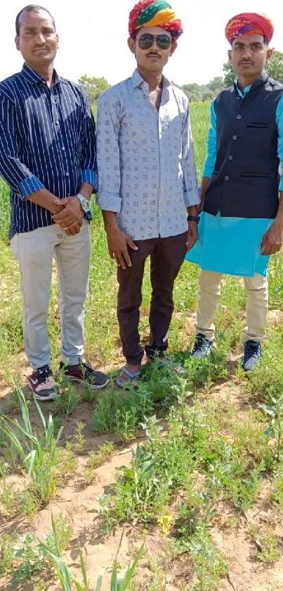 Three figures in colorful traditional attire stand outdoors in a lush green field.