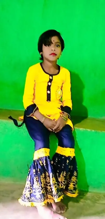 Child in vibrant traditional attire against vivid green wall.