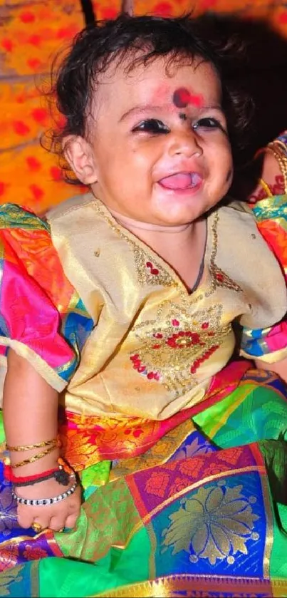 Baby in colorful traditional attire, smiling joyfully.