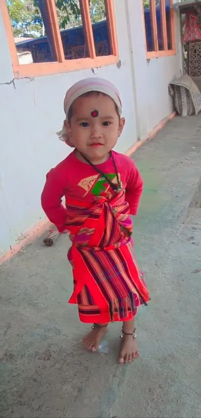 Child in traditional bright attire posing outdoors.