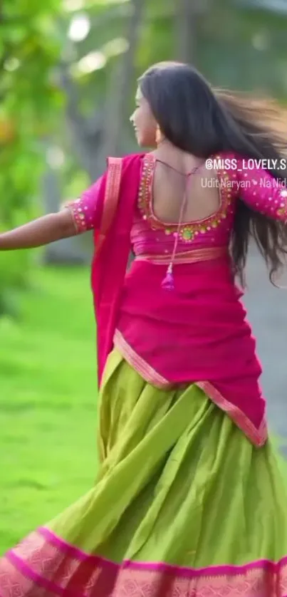 Woman in colorful traditional dress dancing outdoors with a green background.