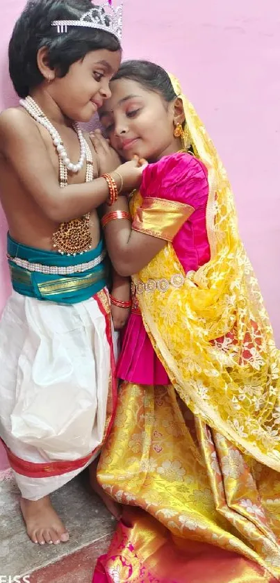 Children in colorful traditional Indian attire against a pink wall.