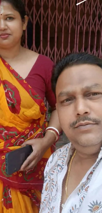 Woman in yellow and red traditional attire with a man beside her.