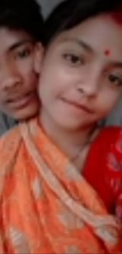 Traditional portrait of two people in vibrant attire with red hues.