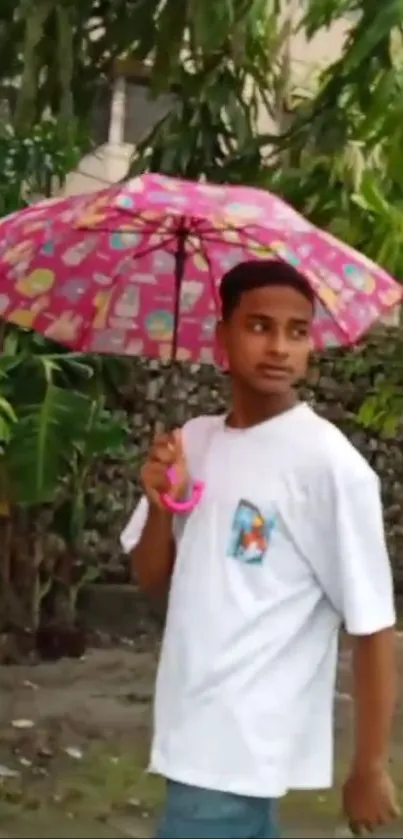 Young man walking with pink umbrella in garden.