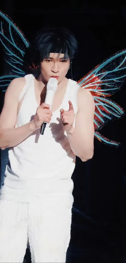 Performer with dazzling wings on stage, singing energetically.