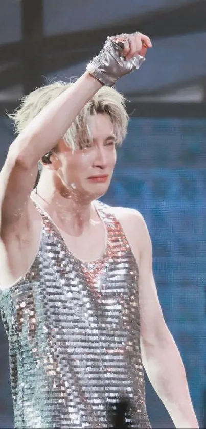 Performer in a glittering silver tank top on stage, capturing a powerful concert moment.