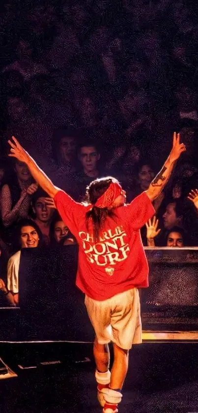 Performer in red shirt on stage with crowd cheering.