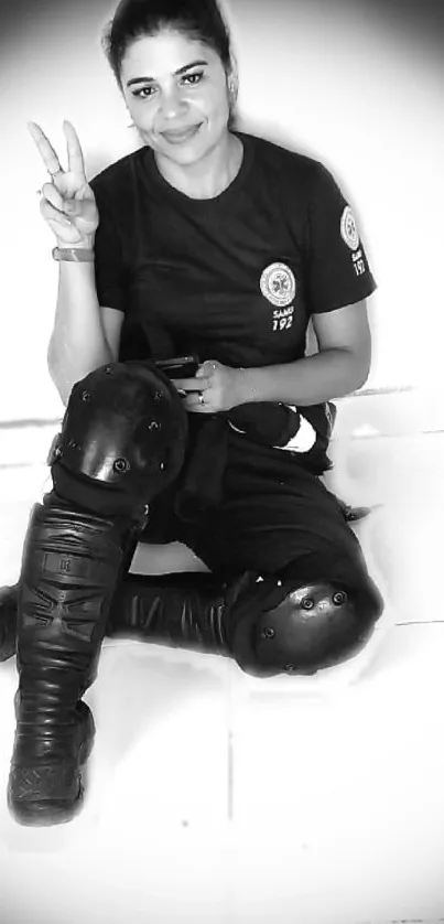 Woman in black gear sitting confidently on a white background.