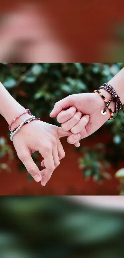 Hands linked with colorful bracelets against a green background.