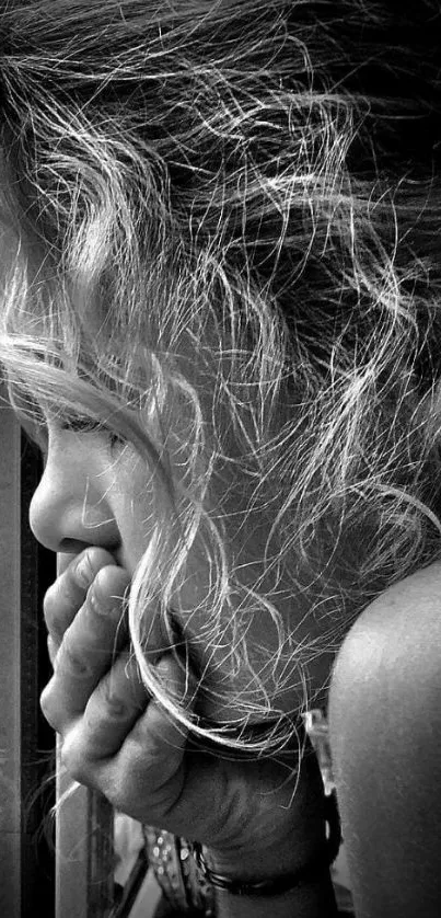 Black and white photo of a woman looking out a window, deep in thought.