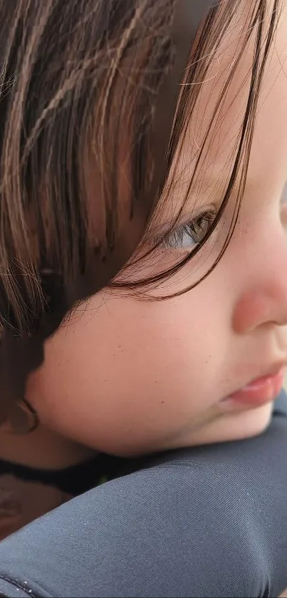 Close-up portrait of a child with soft brown hair looking pensive.