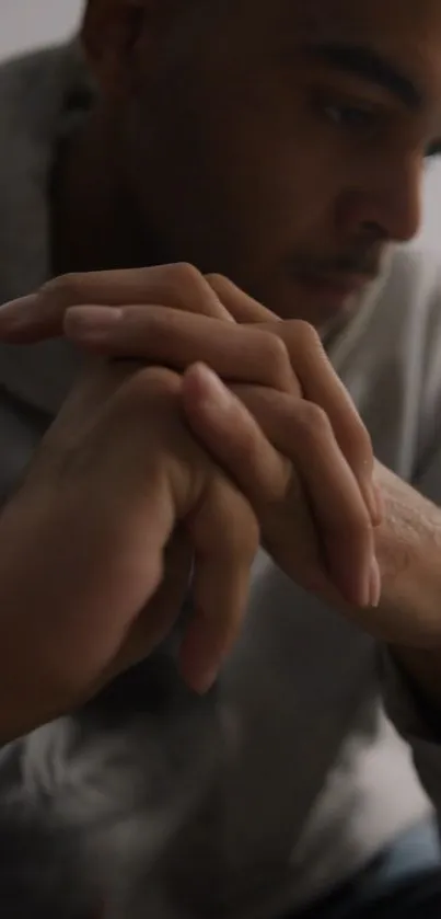 Person in contemplation with folded hands.