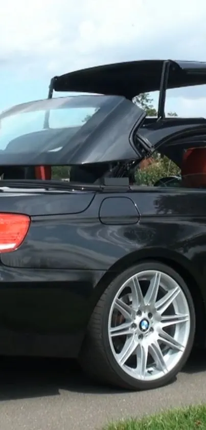 Black convertible car with open roof on the road.