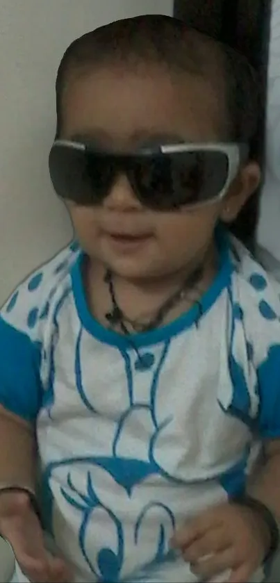 Cute baby wearing sunglasses and a blue shirt.