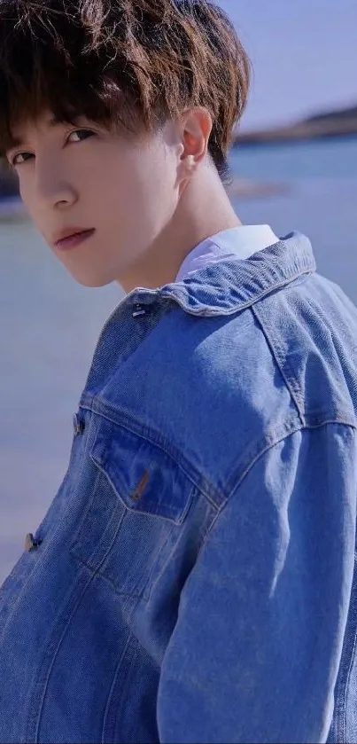 Young person in denim jacket by the coast.