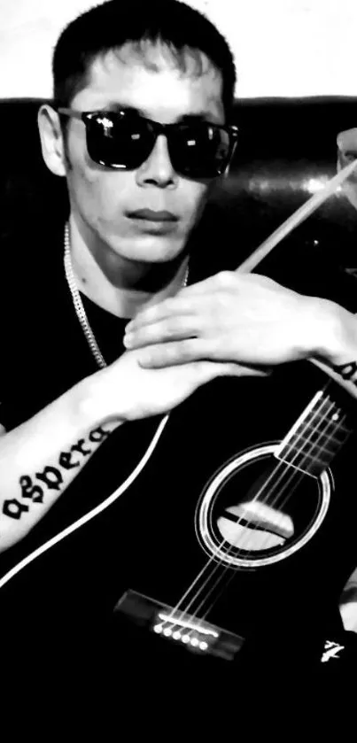 Black and white image of a guitarist in sunglasses, holding a guitar.