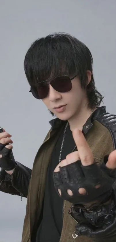 Mysterious person in sunglasses and leather attire with a gray background.