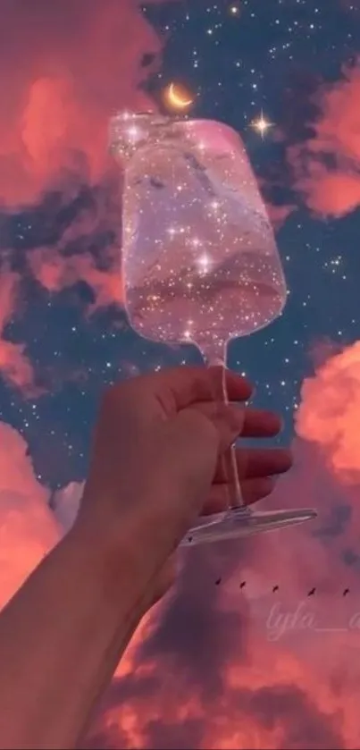 Hand holds galaxy-filled wineglass under a pink starry sky.