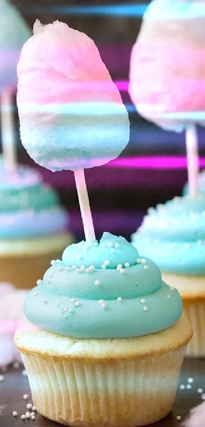 Cupcakes with blue frosting topped with pink cotton candy on a stick.