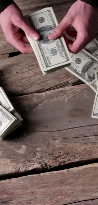 Hands counting dollar bills on rustic wooden table.