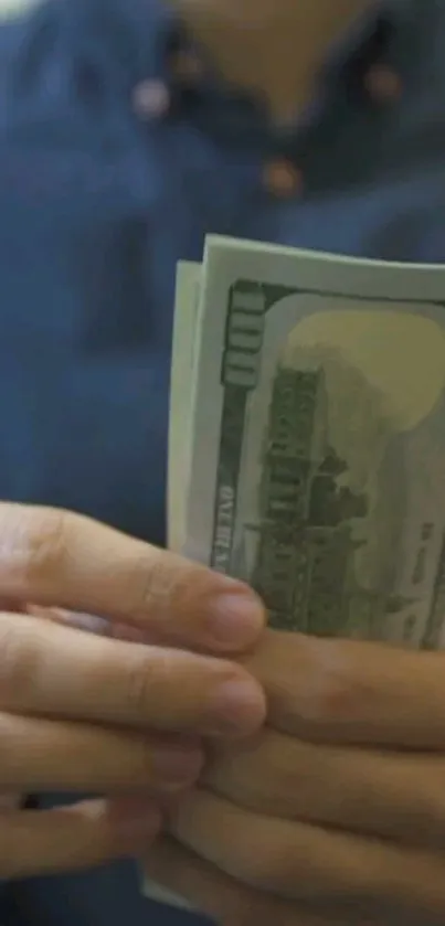 Person counting U.S. hundred-dollar bills in hands.