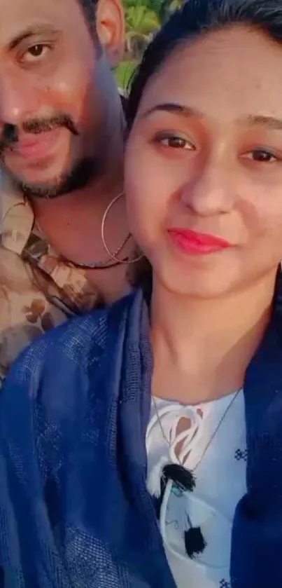 Smiling couple taking a selfie on a sunny beach day.