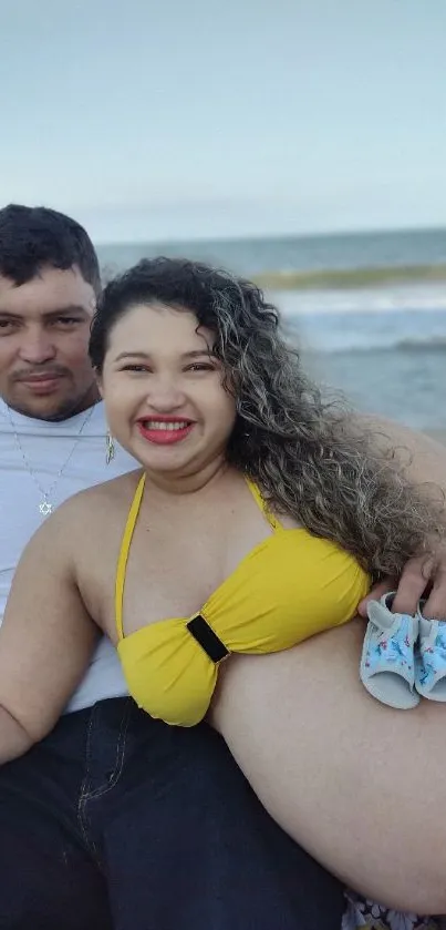 Couple sitting on a beach embracing future parenthood.