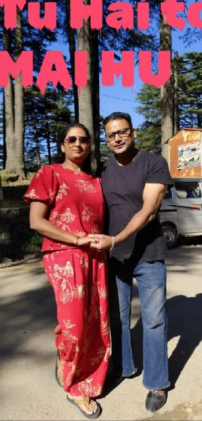 Couple holding hands in a sunlit forest with trees.