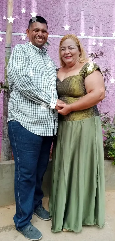 Couple posing in garden by a pink wall.