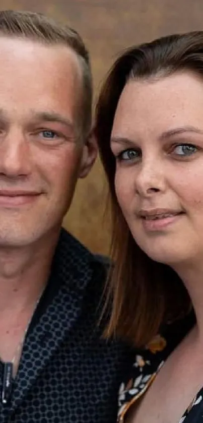 Couple posing against a brown textured backdrop.