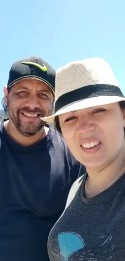 Smiling couple under bright blue sky.