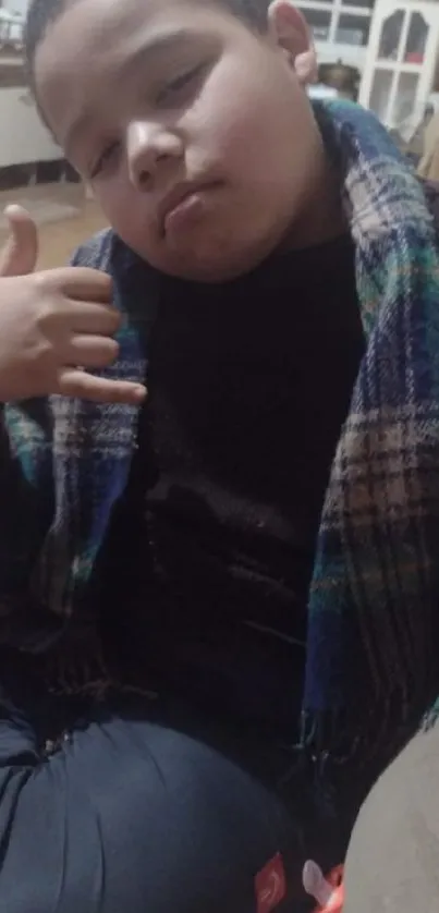 Boy in plaid scarf showing relaxed hand gestures.