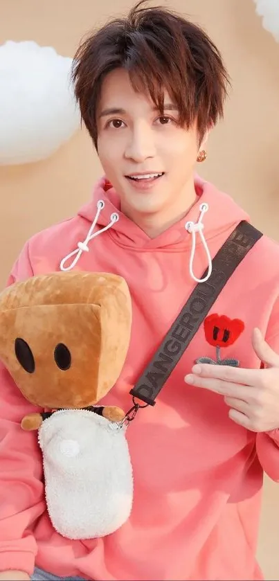 Person in salmon pink hoodie with plush accessory.