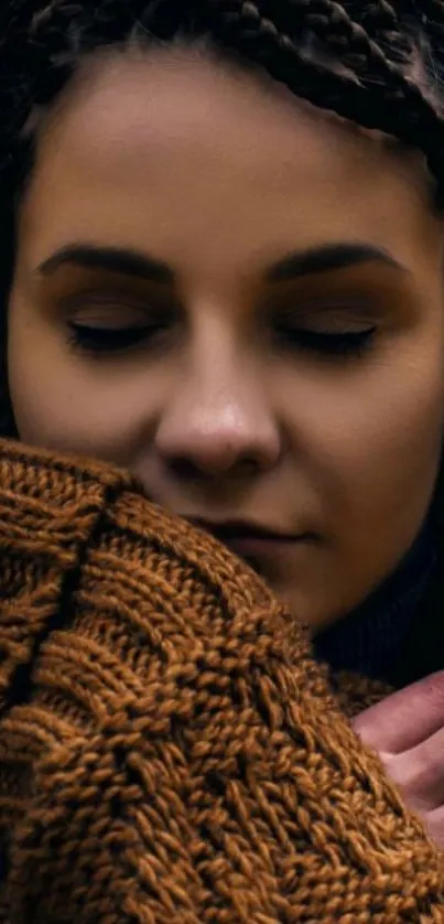 Woman in brown knit sweater with braided hair, eyes closed.