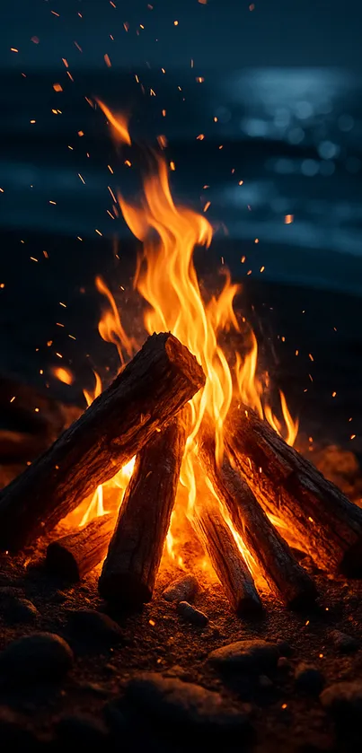 A glowing bonfire on a beach at night by the ocean.