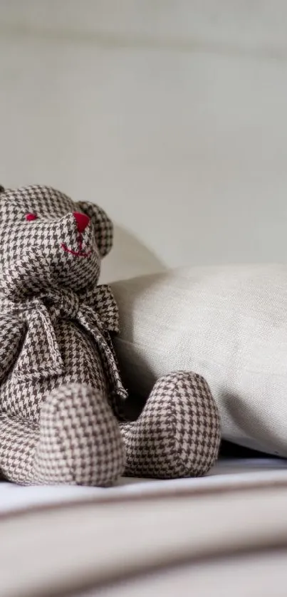 Teddy bear sitting on a neatly made bed with neutral tones.